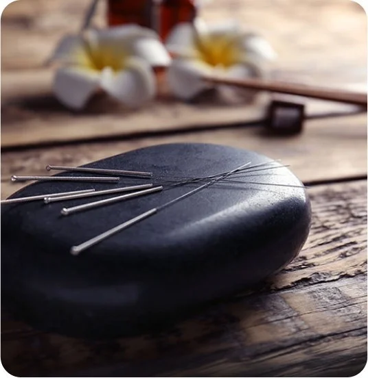 Acupuncture needles on black massage stone
